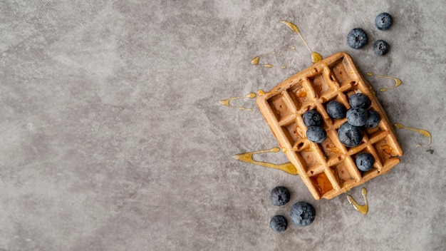 Free photo flat lay of blueberries and honey on top of waffle with copy space