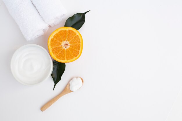 Flat lay of body butter and orange on plain background