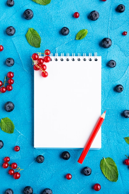 Flat-lay bowl of fresh berries with notepad