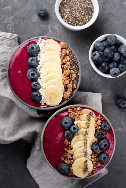 Flat lay of bowls with breakfast desserts and assortment of fruits and cereal