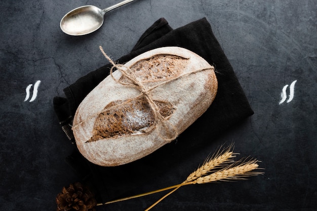 Flat lay of bread and wheat on black background