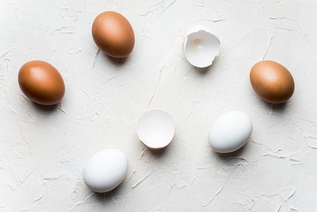 Free photo flat lay broken eggs on white background