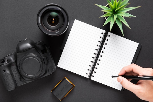 Free photo flat lay of camera lenses and notebook on black background