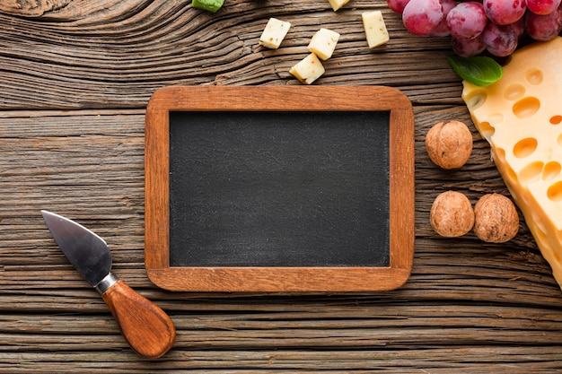 Free photo flat lay cheese grapes walnuts and blank blackboard