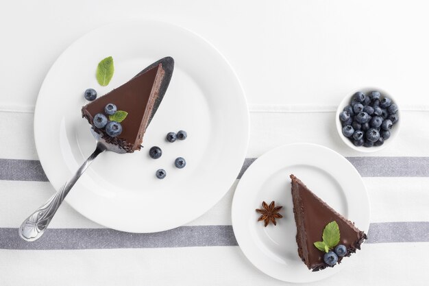 Flat lay of chocolate cake slices on plates with blueberries