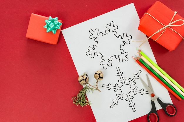 Free Photo flat lay of christmas figures for coloring and trimming on red