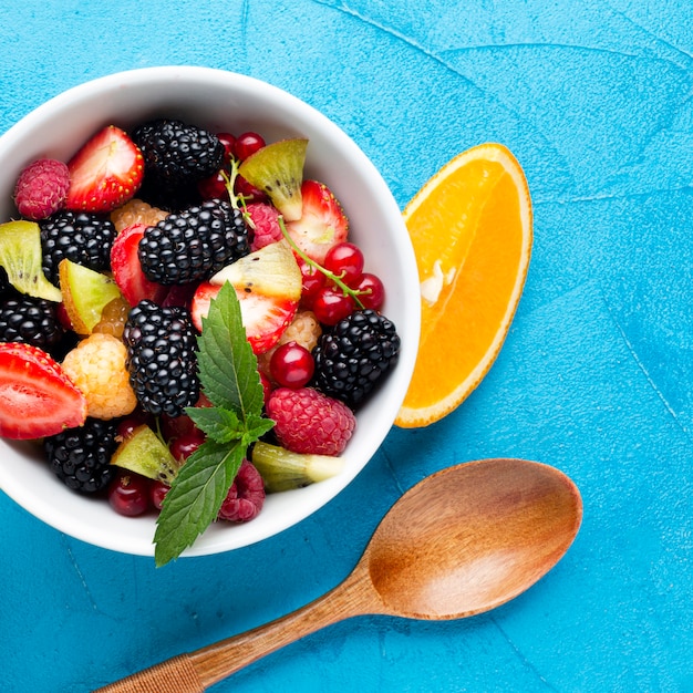 Flat-lay close-up bowl of fresh berries and fruits with spoon