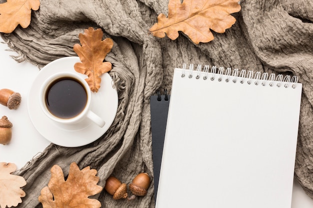 Flat lay of coffee cup with textile and autumn leaves