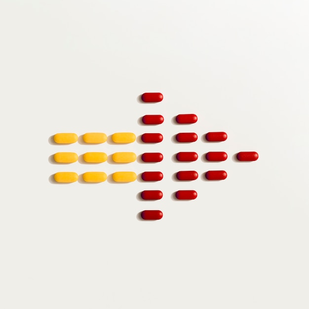 Free Photo flat lay of colored pills forming an arrow