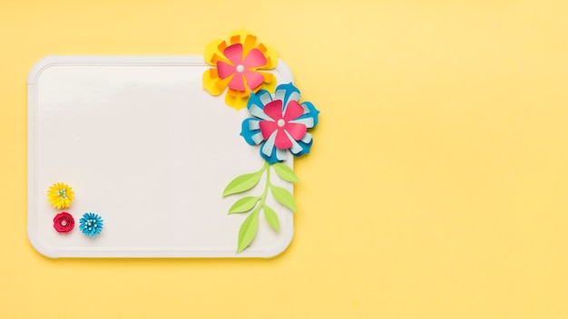 Free photo flat lay of colorful paper flowers on whiteboard