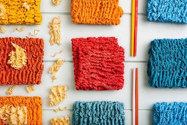 Free photo flat lay colorful ramen noodles and colorful chopsticks