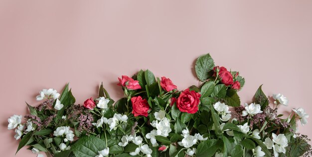 Flat lay composition with fresh flowers on pink background.