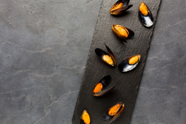 Flat-lay cooked mussels on slate with copyspace