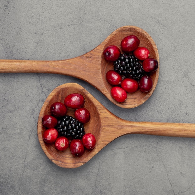 Free Photo flat lay of cranberries and blueberries in wooden spoon