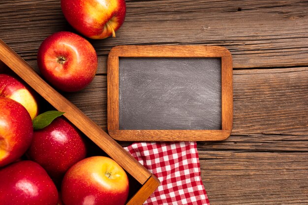 Free photo flat-lay crate with ripe apples with blackboard