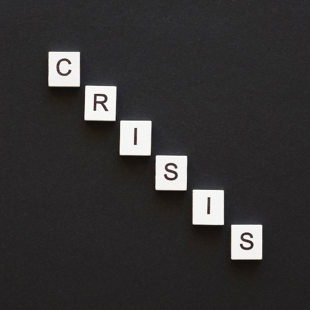 Free photo flat lay crisis word written on wooden cubes