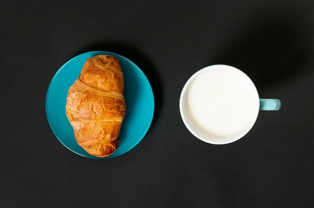 Free photo flat lay croissant and cup of milk on plain background