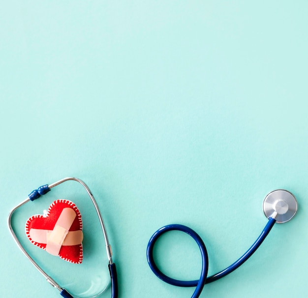 Flat lay of damaged heart shape with stethoscope and copy space