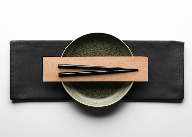 Flat lay of dark dinnerware with chopsticks and napkin