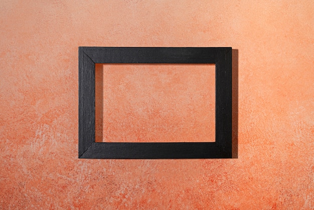 Free photo flat lay dark frame on orange background