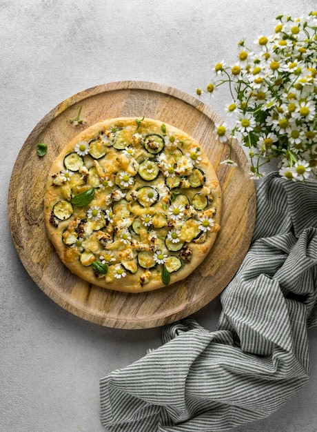 Free photo flat lay of delicious cooked pizza with bouquet of chamomile flowers