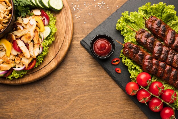 Flat lay of delicious kebab on slate with other dishes and ketchup