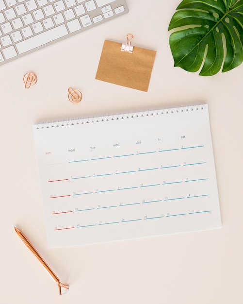 Flat lay desk calendar with monstera leaf and pencil box