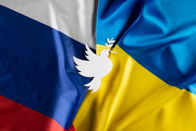 Free photo flat lay dove shape on ukrainian and russian flags