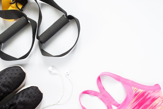 Flat lay of earphone, red dumbbells and sport equipment on white background. Sport wear,  top view