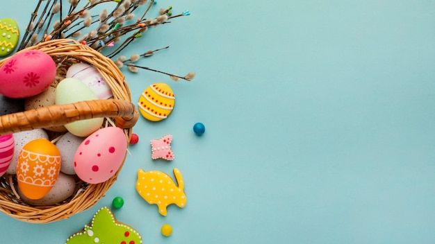 Flat lay of easter eggs in basket with bunny and butterfly shapes