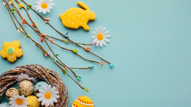 Free photo flat lay of easter eggs in basket with chamomile flowers and bunny