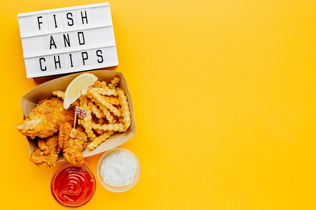 Flat lay of fish and chips with sauce and light box