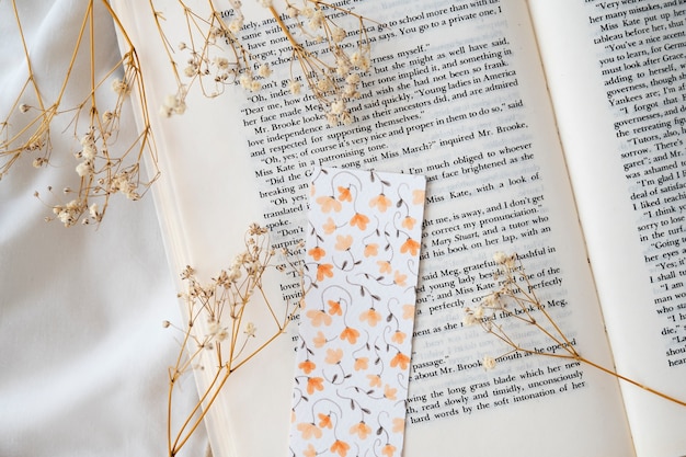 Free photo flat lay floral bookmark on book