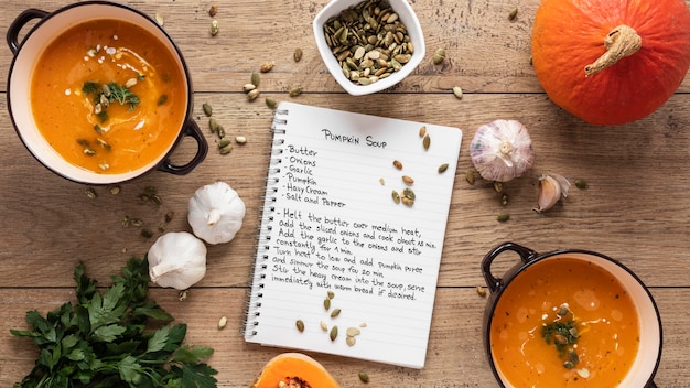 Flat lay of food ingredients with pumpkin soup and notebook