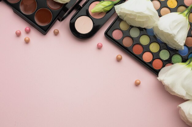 Flat lay frame with flowers and make-up palettes