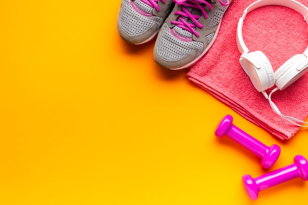 Flat lay frame with pink items on yellow background