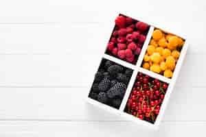 Free photo flat-lay fresh berries in tray with copyspace