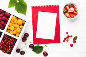 Free photo flat-lay fresh berries with notepad