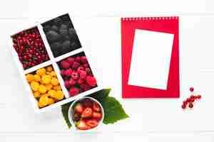 Free photo flat-lay fresh berries with notepad