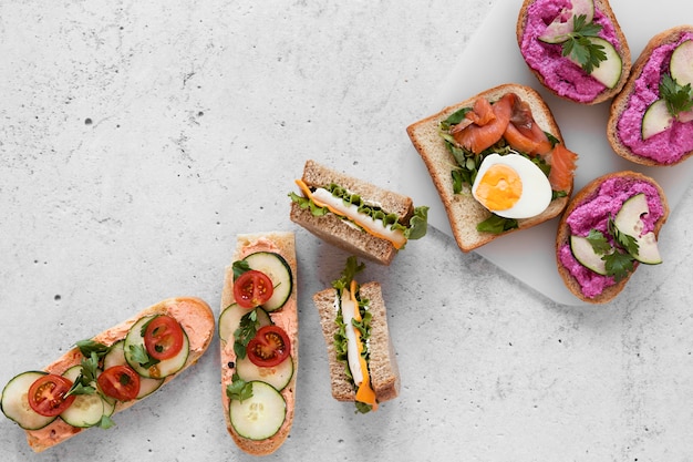 Free photo flat lay fresh sandwiches assortment on cement background