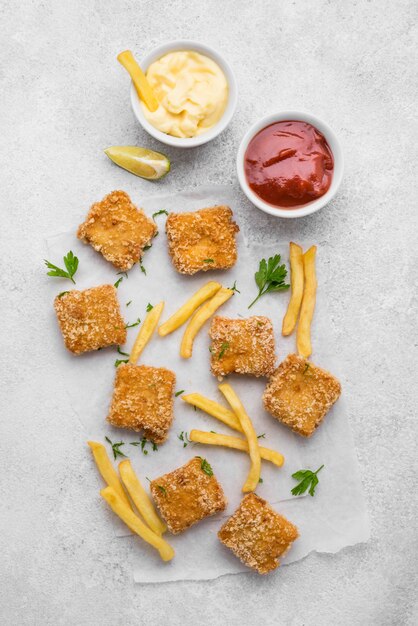 Free photo flat lay of fried chicken nuggets with sauces and french fries