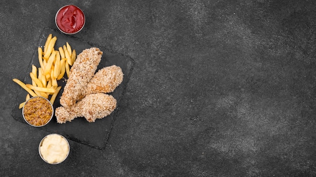 Flat lay of fried chicken with french fries and sauces