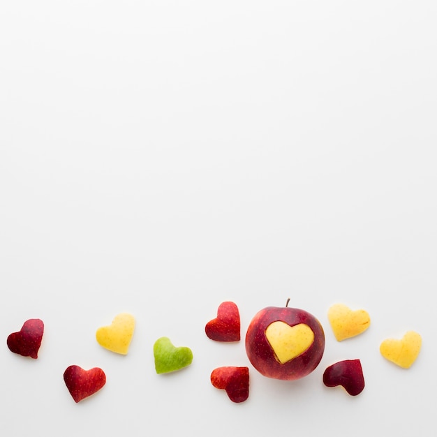 Flat lay of fruit heart shapes and apple with copy space