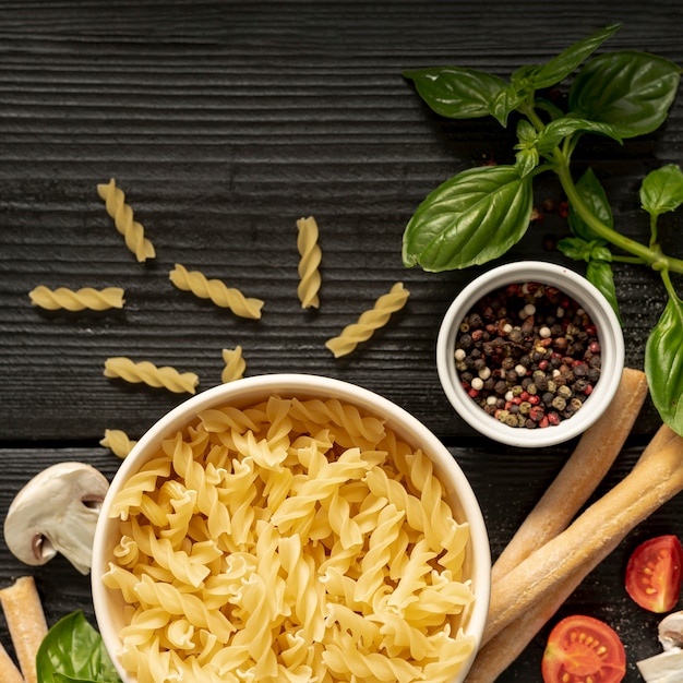 Free photo flat lay of fusilli pasta pepper and grissini on wooden table