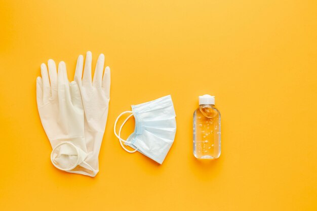 Flat lay of gloves with medical mask and hand sanitizer