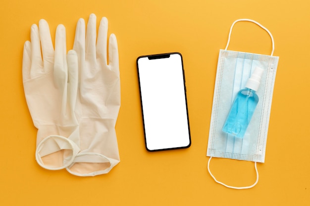 Free Photo flat lay of gloves with smartphone and hand sanitizer