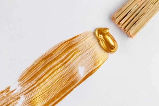 Flat lay of golden paint and brush