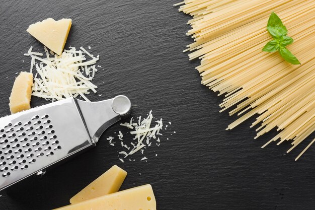 Free photo flat lay grated parmesan and grater with uncooked spaghetti