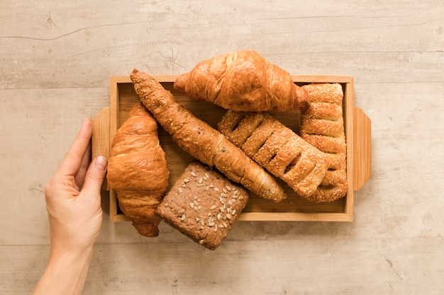 Flat lay hand holding mix of pastry in wooden box