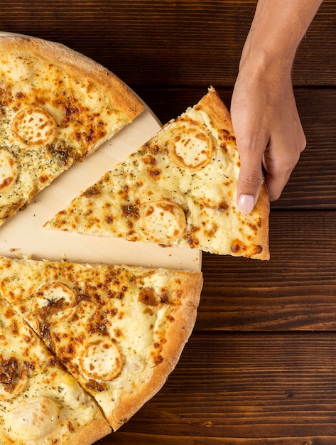 Free photo flat lay hand taking slice of pizza with cheese